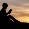 silhouette of child sitting behind tree during sunset