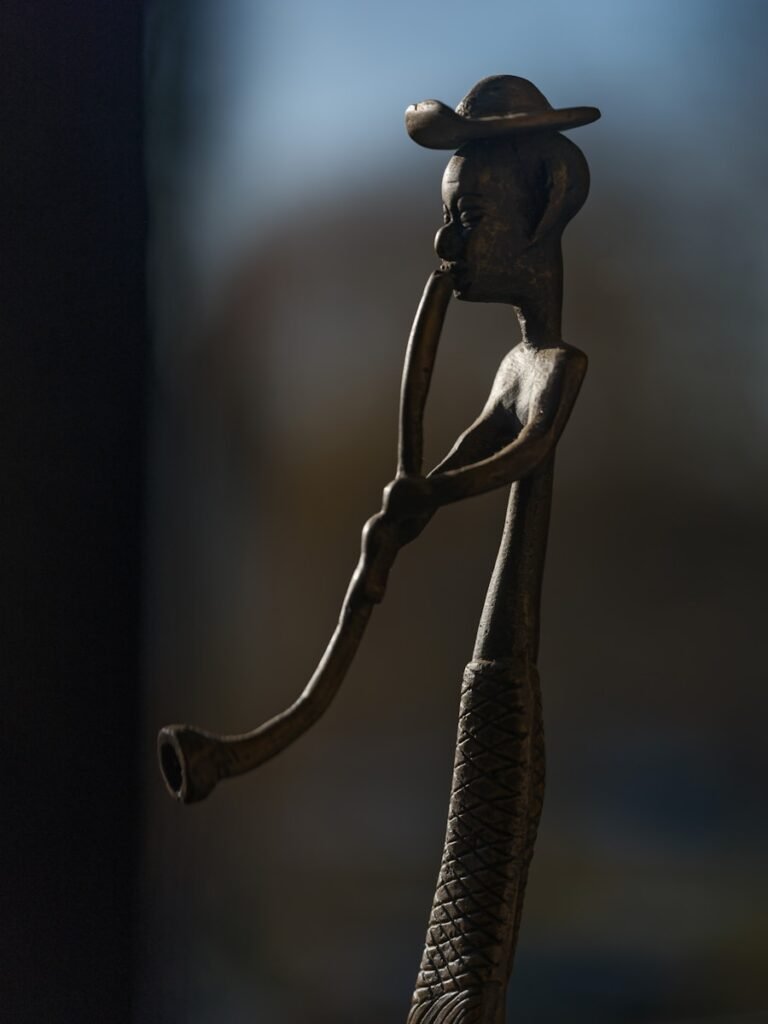 Wooden statue of a man playing a long pipe.