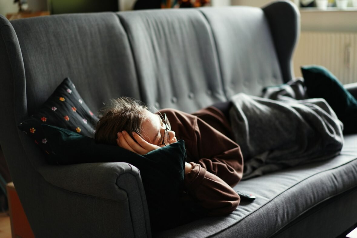 woman in pink jacket lying on gray couch. The Attention Economy