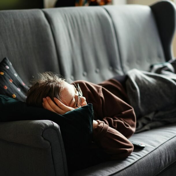 woman in pink jacket lying on gray couch. The Attention Economy